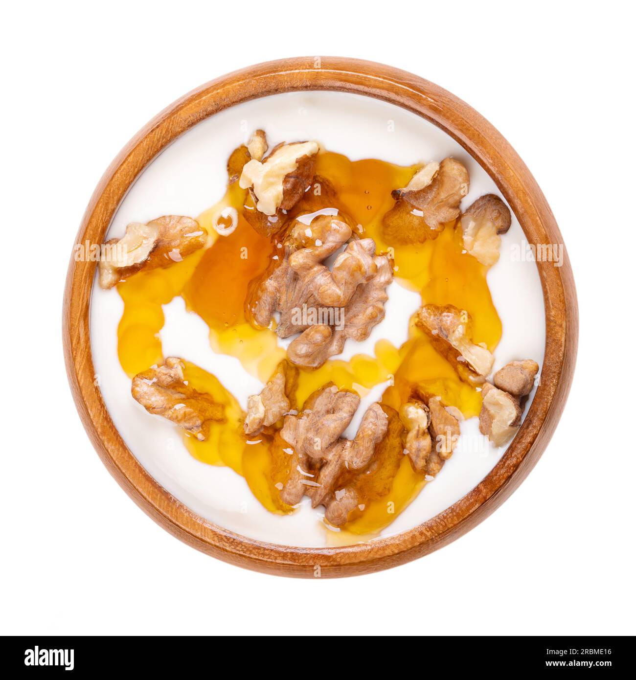 Greek yogurt with honey and roasted walnuts, in a wooden bowl. Yiaourti me meli, traditional little treat, dessert and snack. Stock Photo