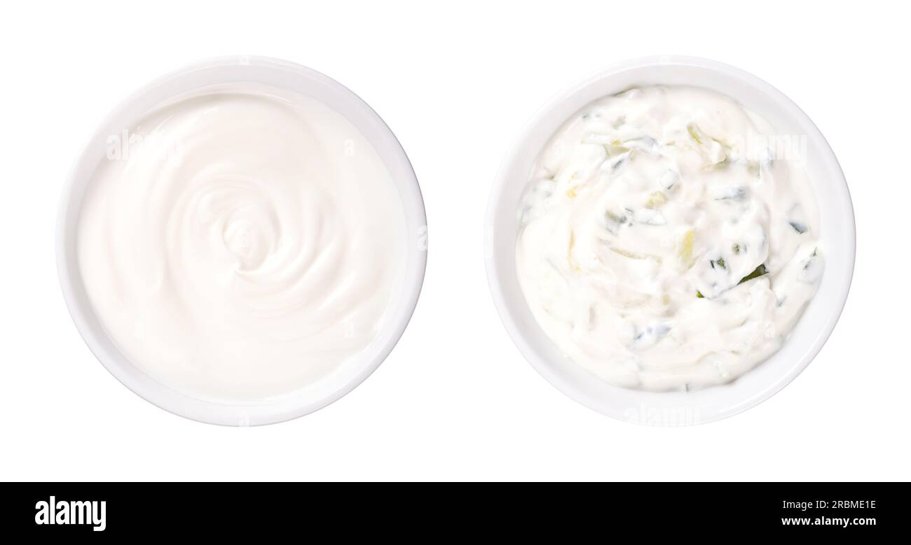 Cream yogurt and tzatziki, in white bowls. Stirred cream yoghurt with high fat content. Pure (left side), and as Greek dip sauce. Stock Photo