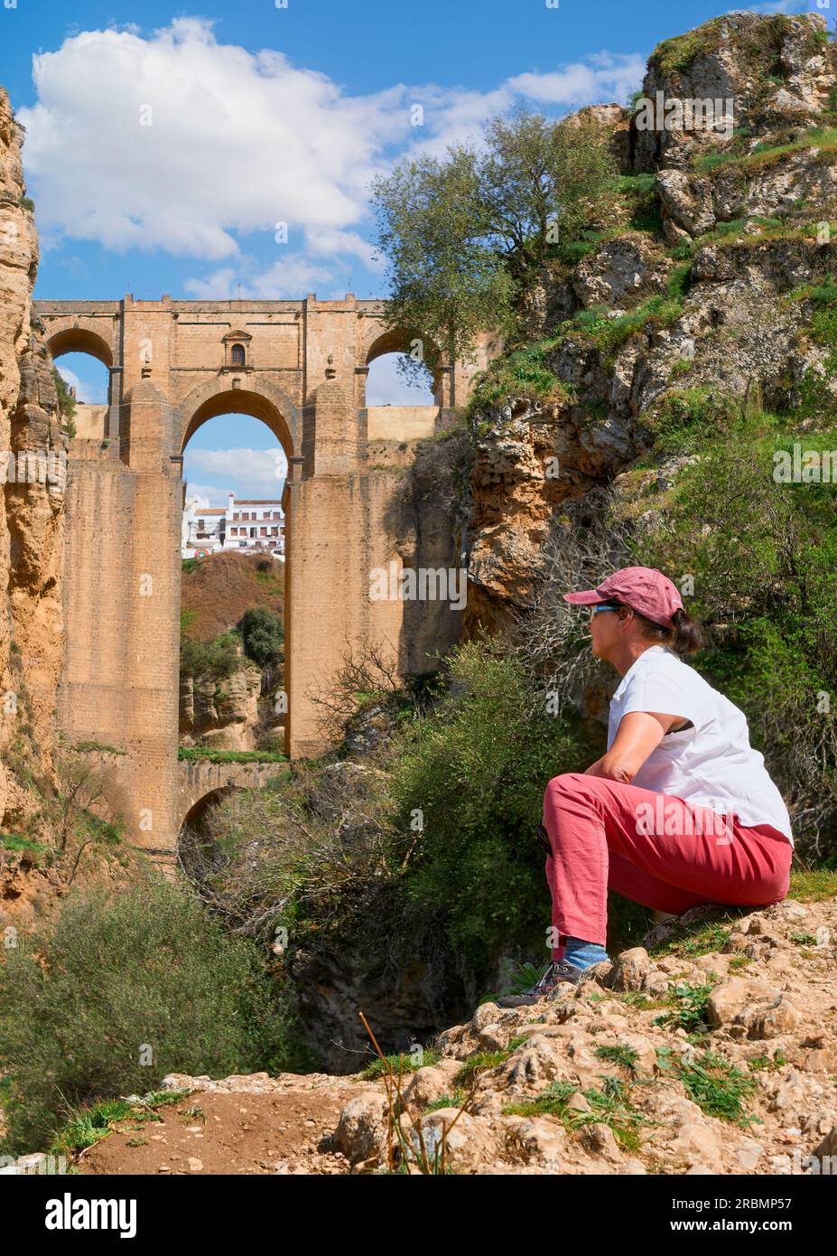 nice, active senior woman resting during a hike below the famous New Bridge of Ronda, Anslusia, Spain Stock Photo