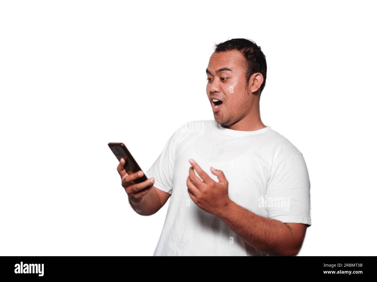 Excited Asian man wearing white Tshirt smiling while holding his phone, isolated by white background Stock Photo