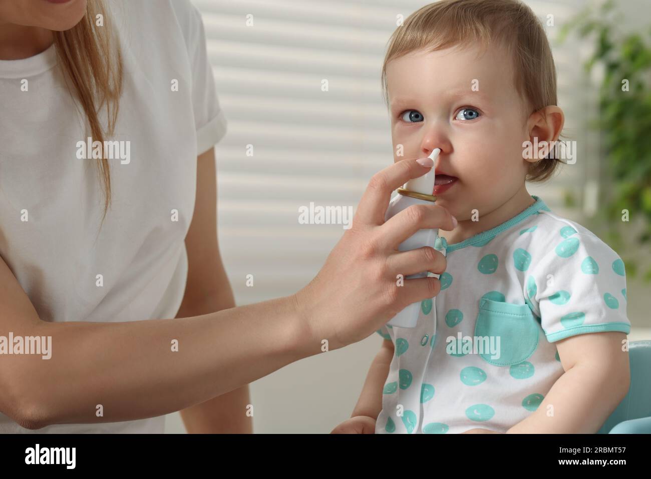 Mother helping her baby to use nasal spray indoors Stock Photo Alamy
