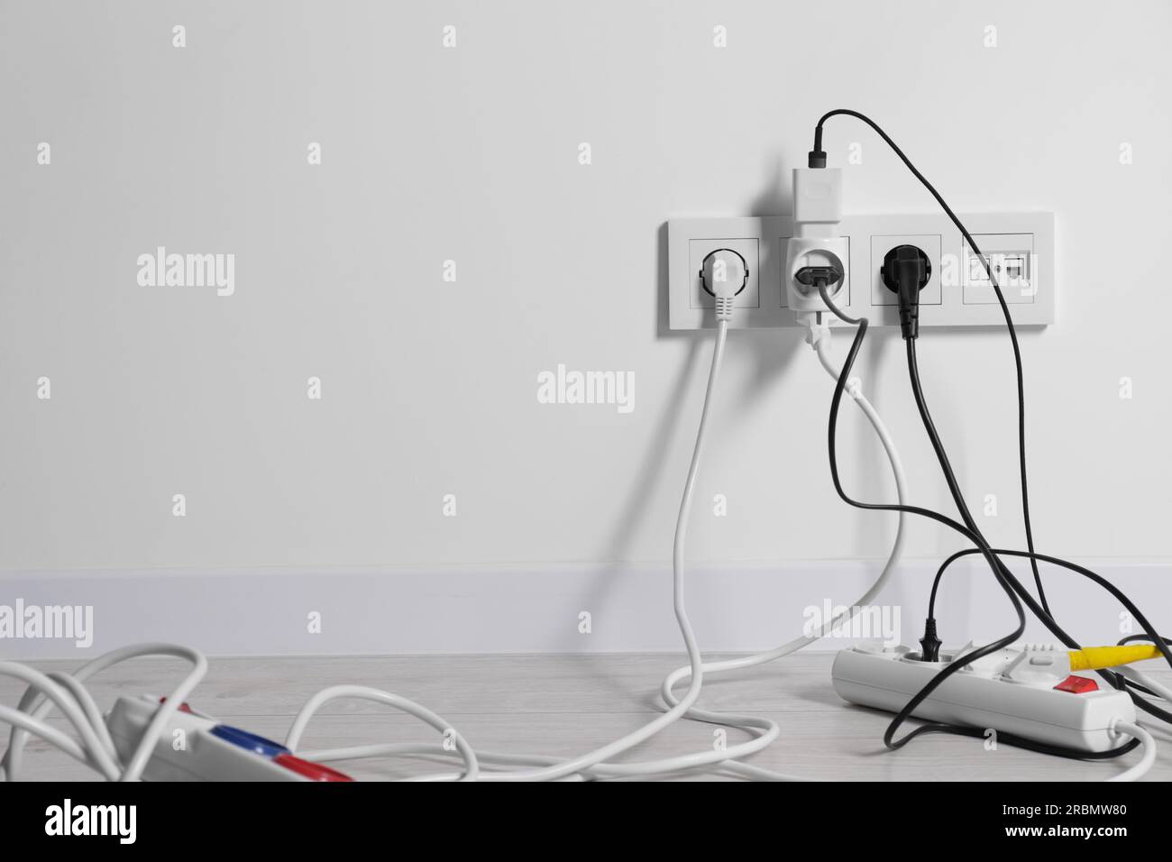 Different electrical plugs in sockets and power strip on floor indoors