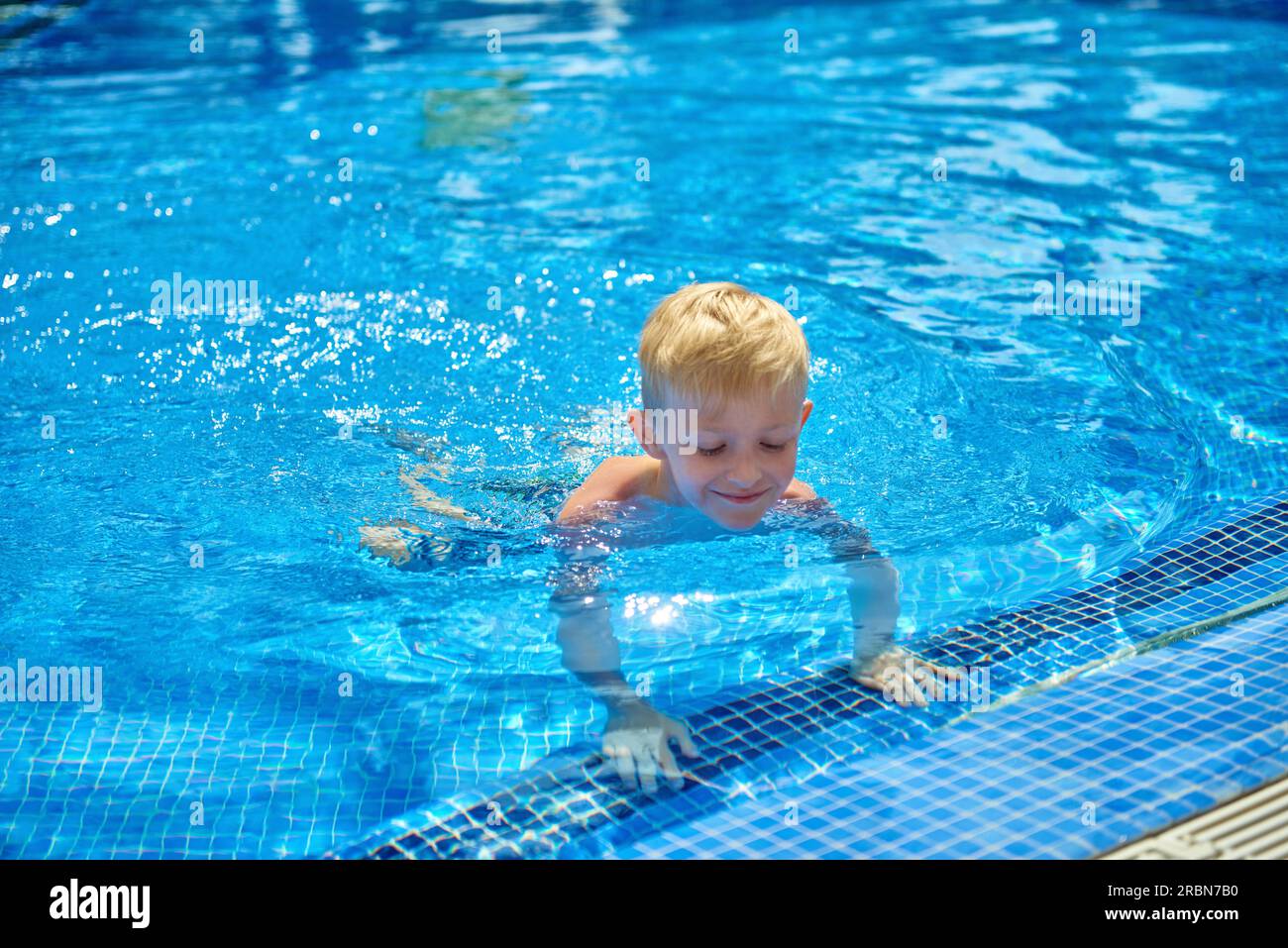Young boy kid child eight years old splashing in swimming pool having