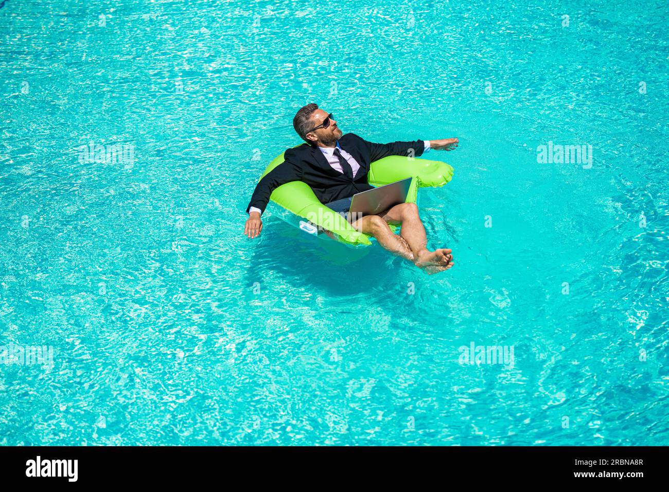 man trader work and relax in swimming pool water. man trader work and relax with laptop. photo of man trader work and relax in pool. man trader work a Stock Photo