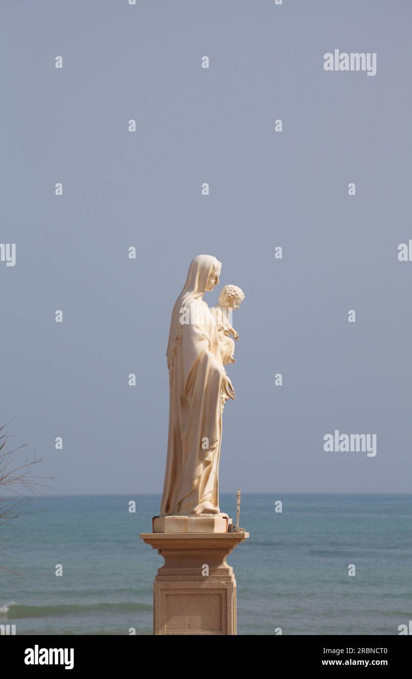 Statue of Mary and Jesus overlooking the little harbour of Punta Secca village, Sicily, Italy, made famous as Marinella in the Montalbano detective series Stock Photo