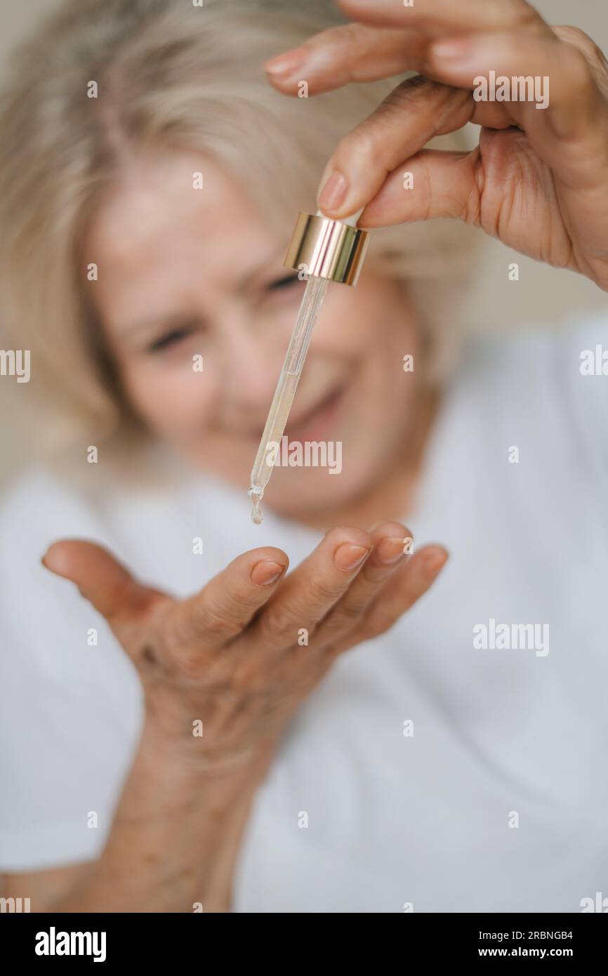 Crop anonymous female applying hyaluronic acid on her hand. Stock Photo
