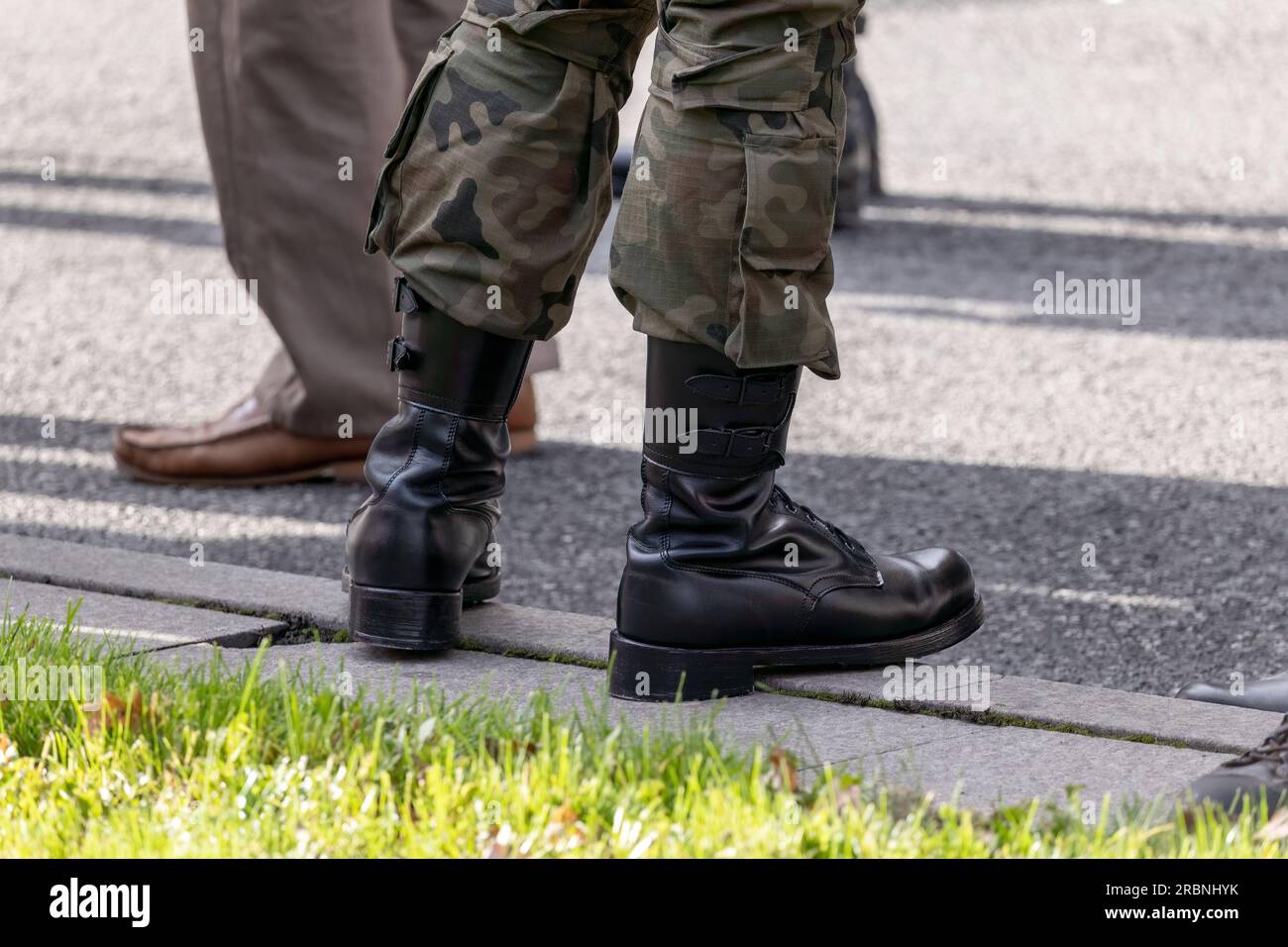 One single anonymous unrecognizable professional soldier standing on the street in traditional generic camo uniform and black boots, closeup detail, a Stock Photo