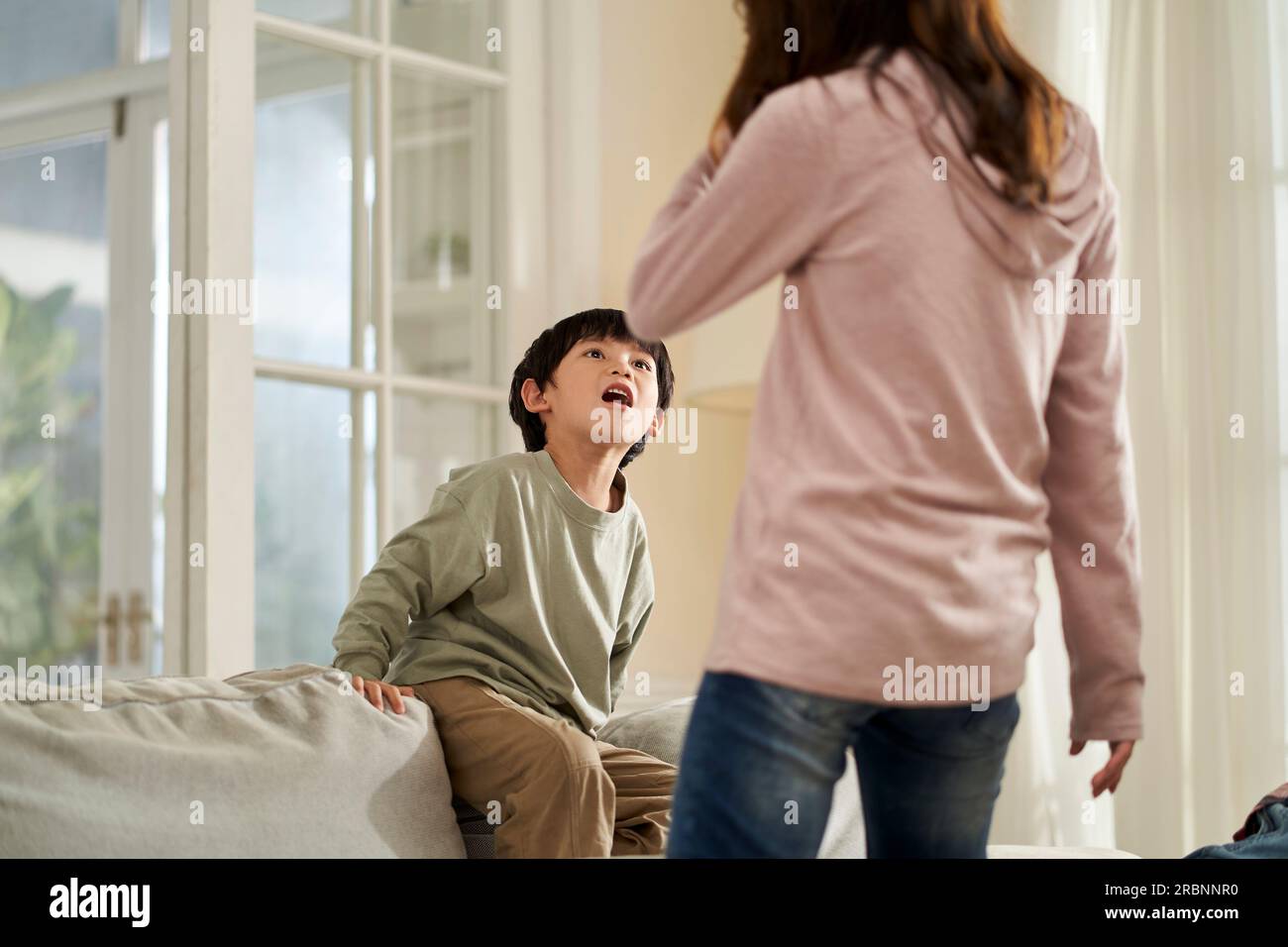 young asian mother and naughty son getting confrontational at home Stock Photo