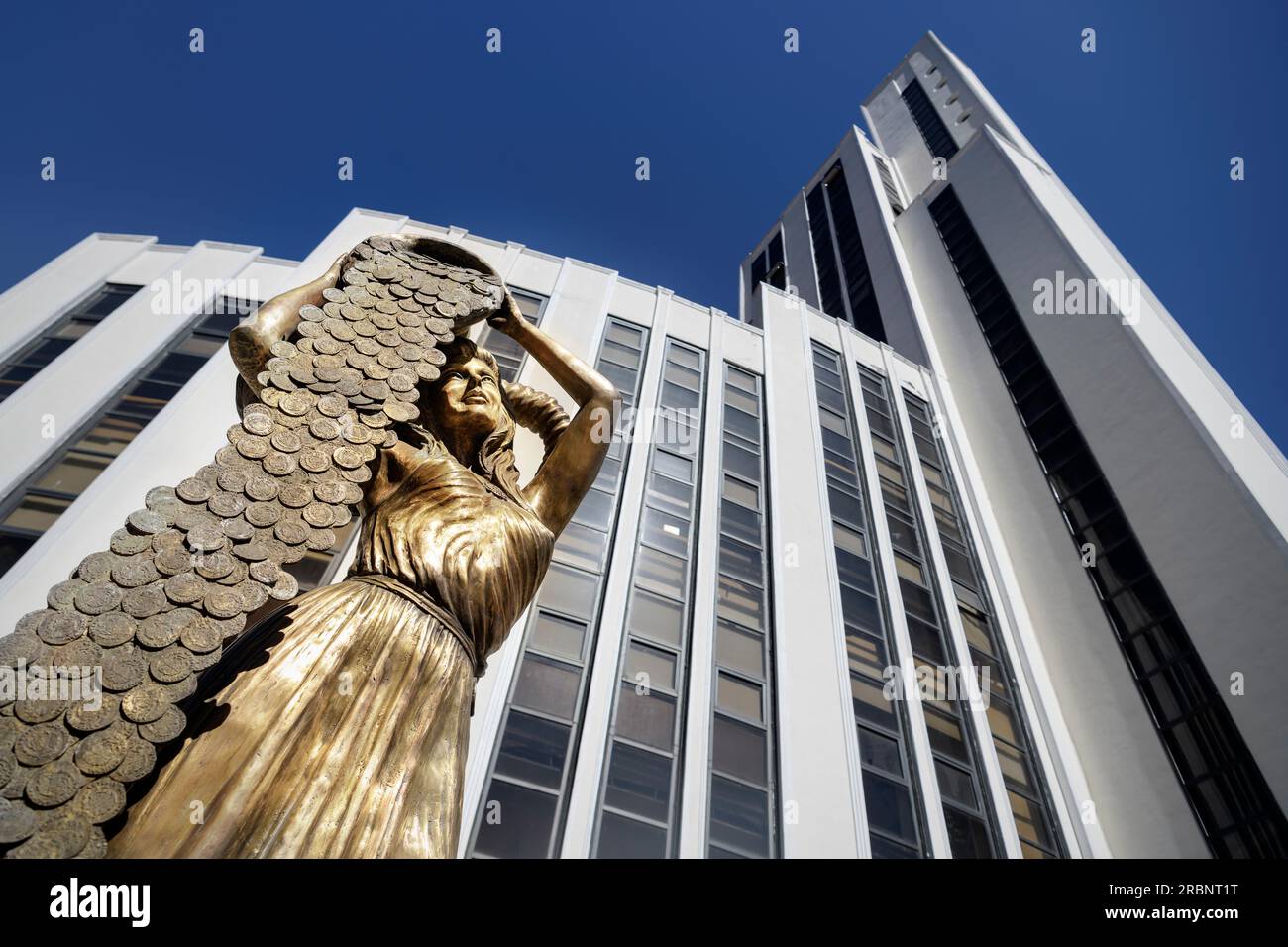 Woman (bronze sculpture) pours money coins from bucket in front of modern office building in Mexico City, Mexico, North America, Latin America, UNESCO Stock Photo