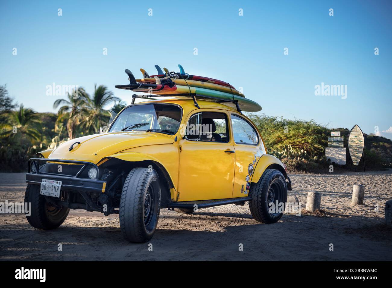 Offroad capable VW Beetle with surfboards on the roof at the surf spot
