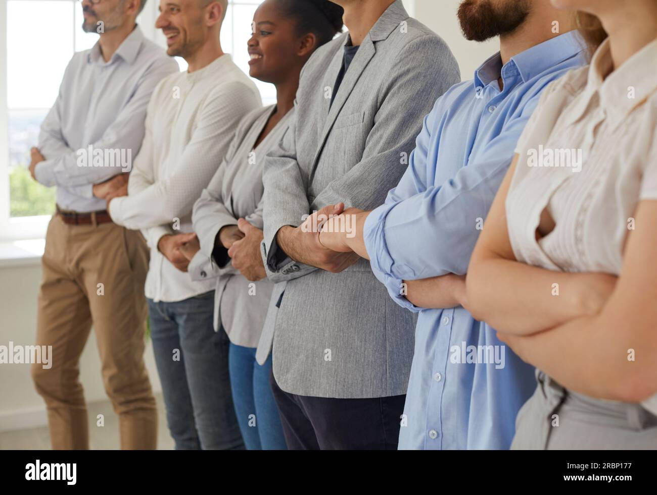 Multiracial business team standing in row joining their hands Stock Photo