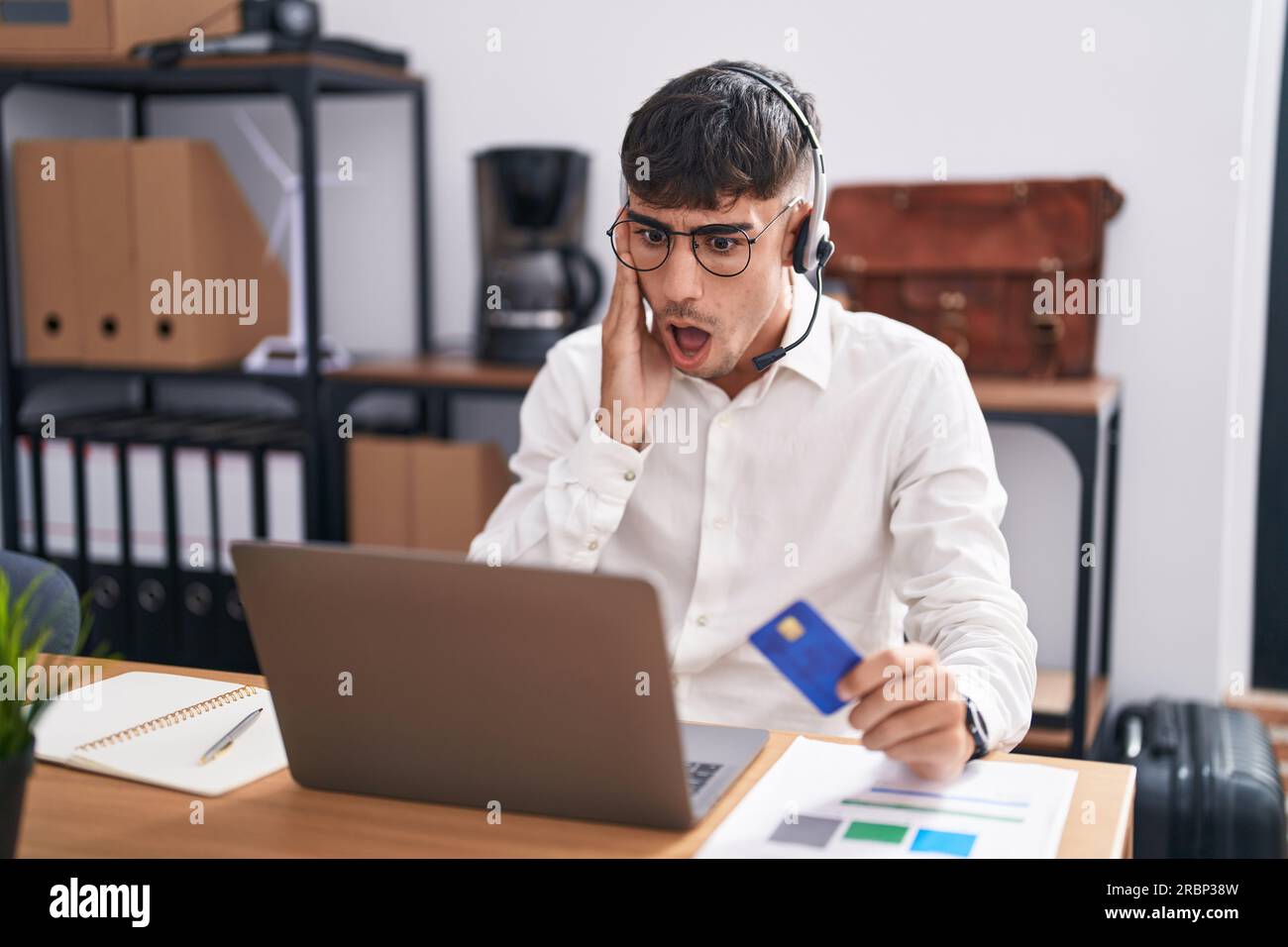 Reading Computer Amazed Young hispanic man working using computer laptop holding credit card ...