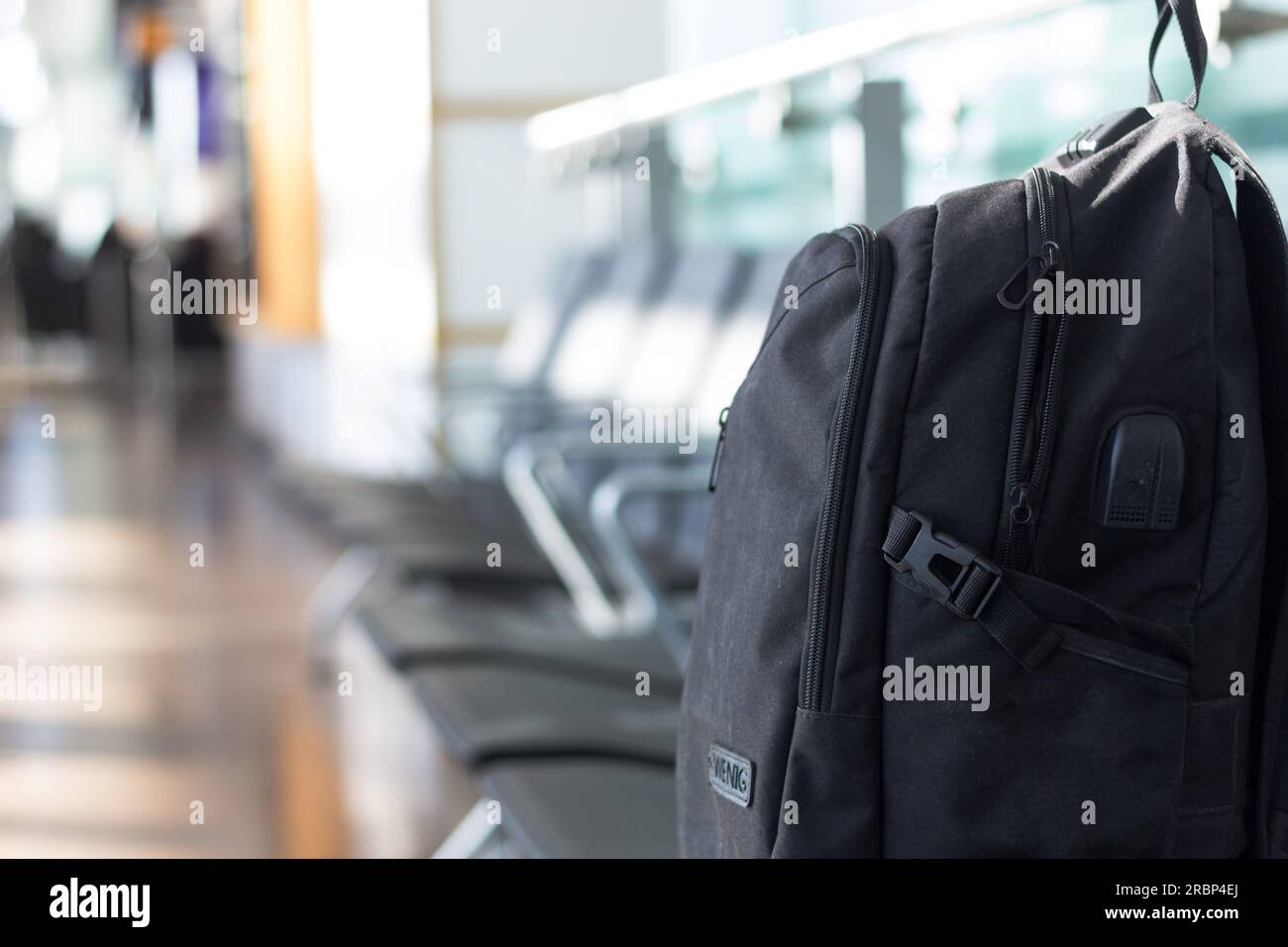 A black rucksack left in an empty row of seating in a modern airport ...