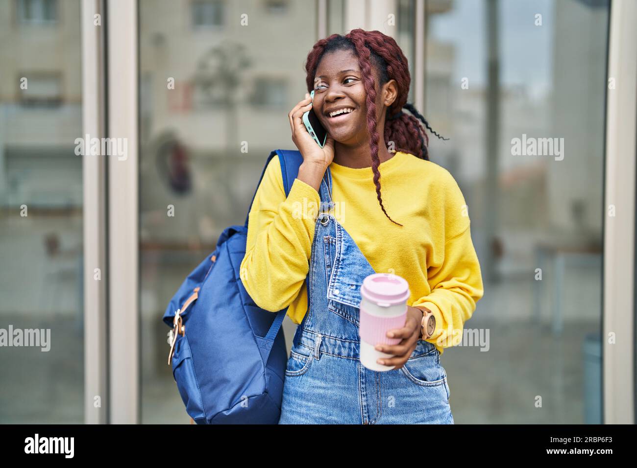 African american woman student talking on smartphone drinking coffee at ...