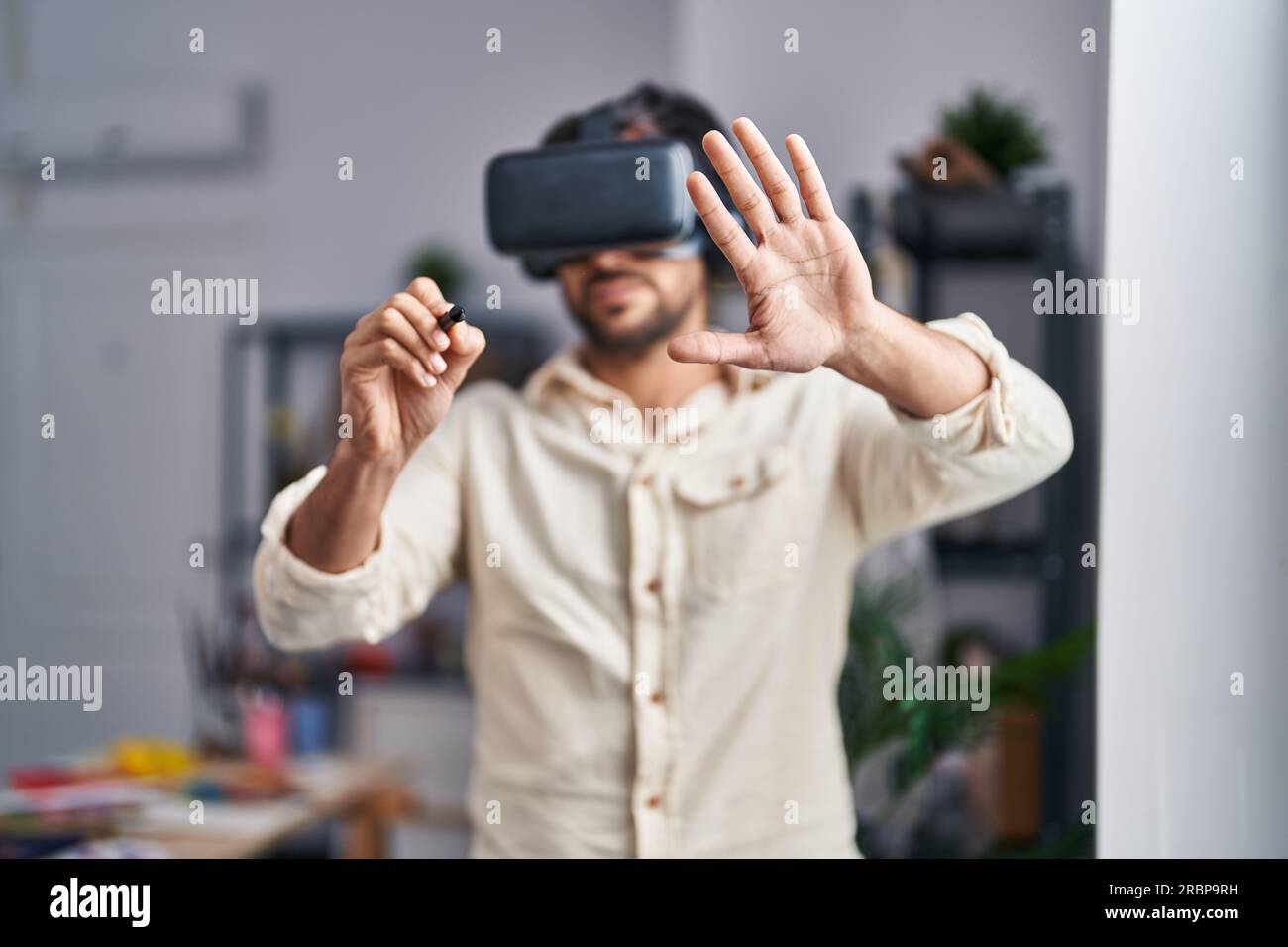 Young hispanic man artist using virtual reality glasses drawing at art studio Stock Photo