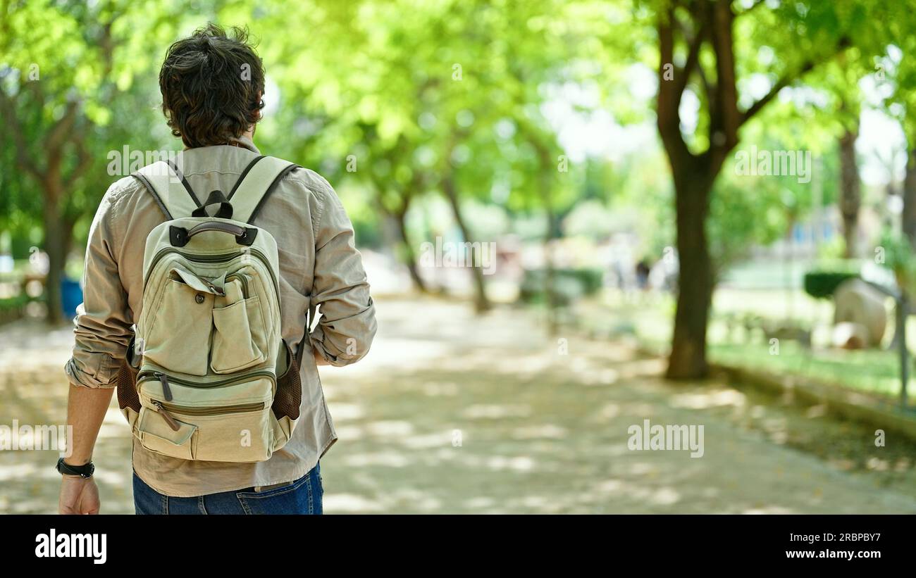 Young hispanic man tourist wearing backpack walking backwards at park Stock  Photo - Alamy, image size:1300x821