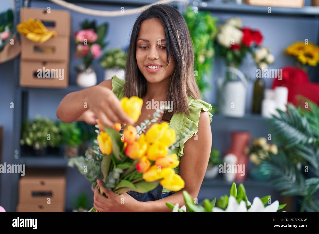 Young hispanic woman florist holding bouquet of flowers at florist ...