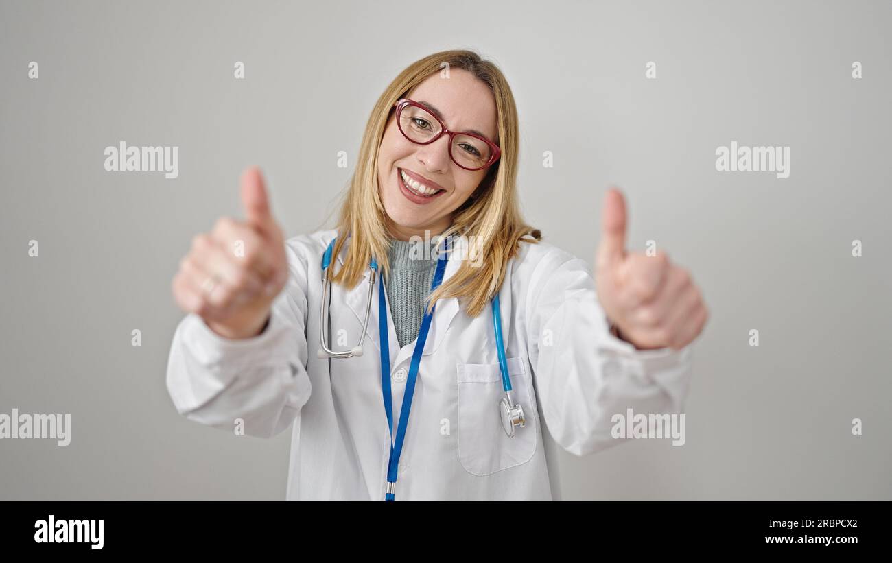 Young blonde woman doctor doing thumbs up over isolated white ...