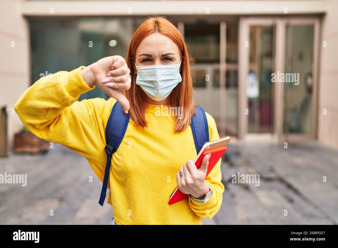 Young woman wearing safety mask and student backpack holding books with ...