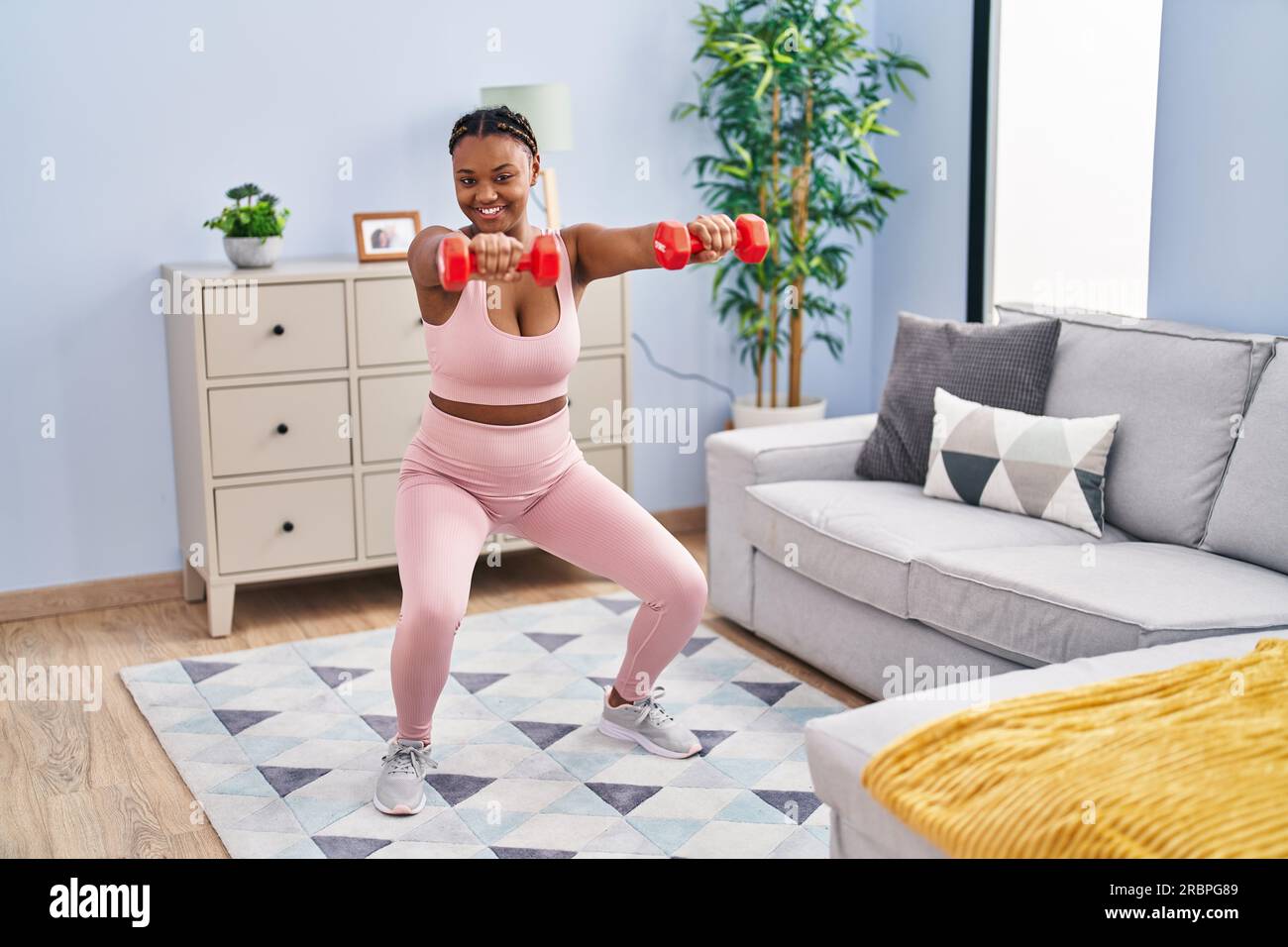 African american woman training leg exercise using dumbbells at home ...