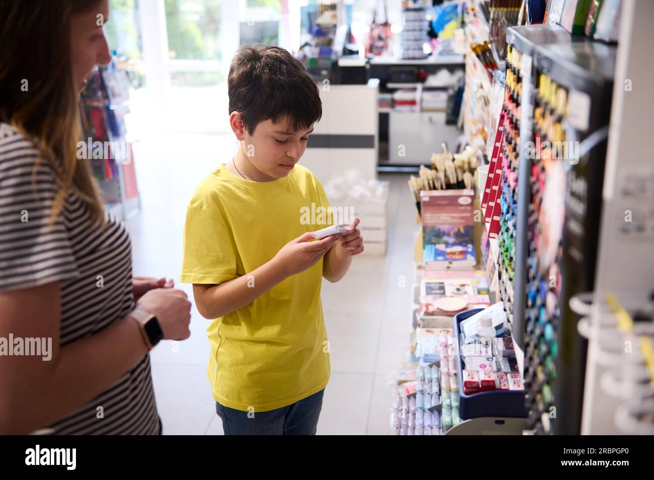 Multi-ethnic adorable teen boy 11-14 years old, choosing modeling clay in a school stationery store. People. Creative hobby. Education. Fine art. Prep Stock Photo