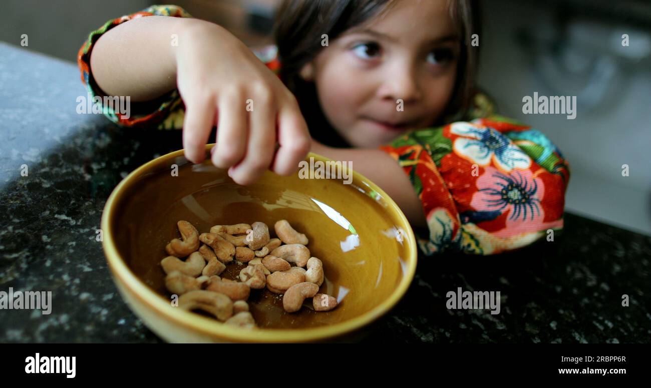 Little girl eating cashew nuts from bowl child eats healthy snack food