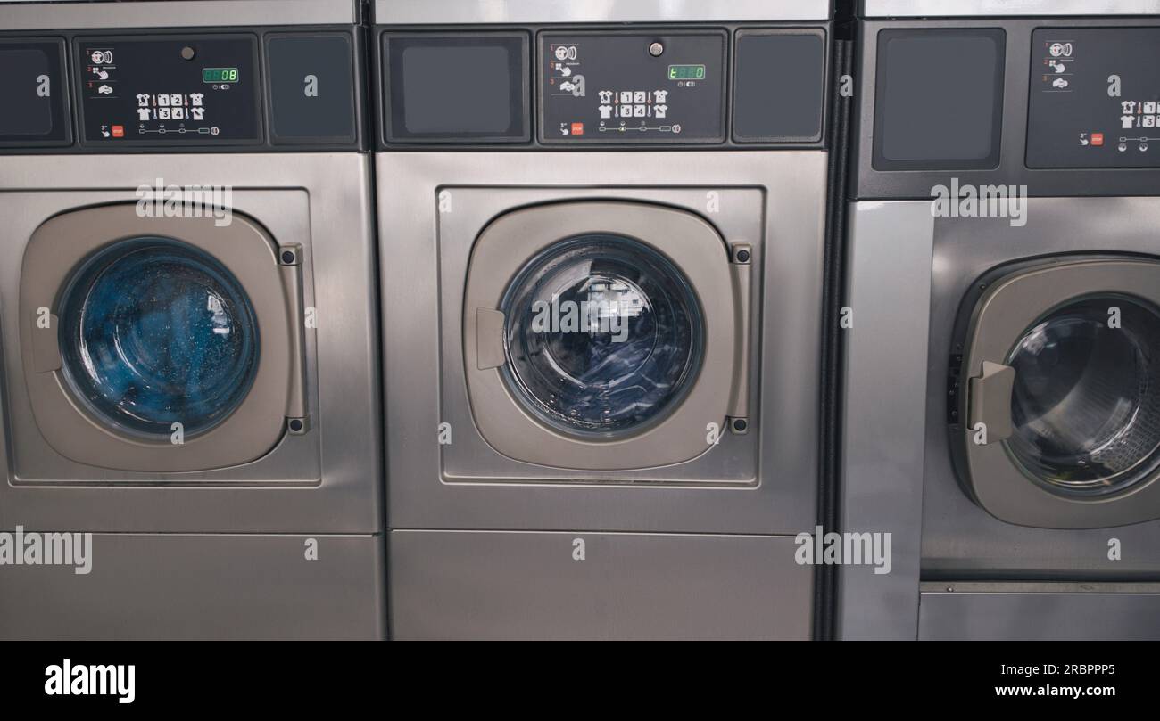 Three Industrial Washing Machines In Laundromat In A Row Indoors Stock