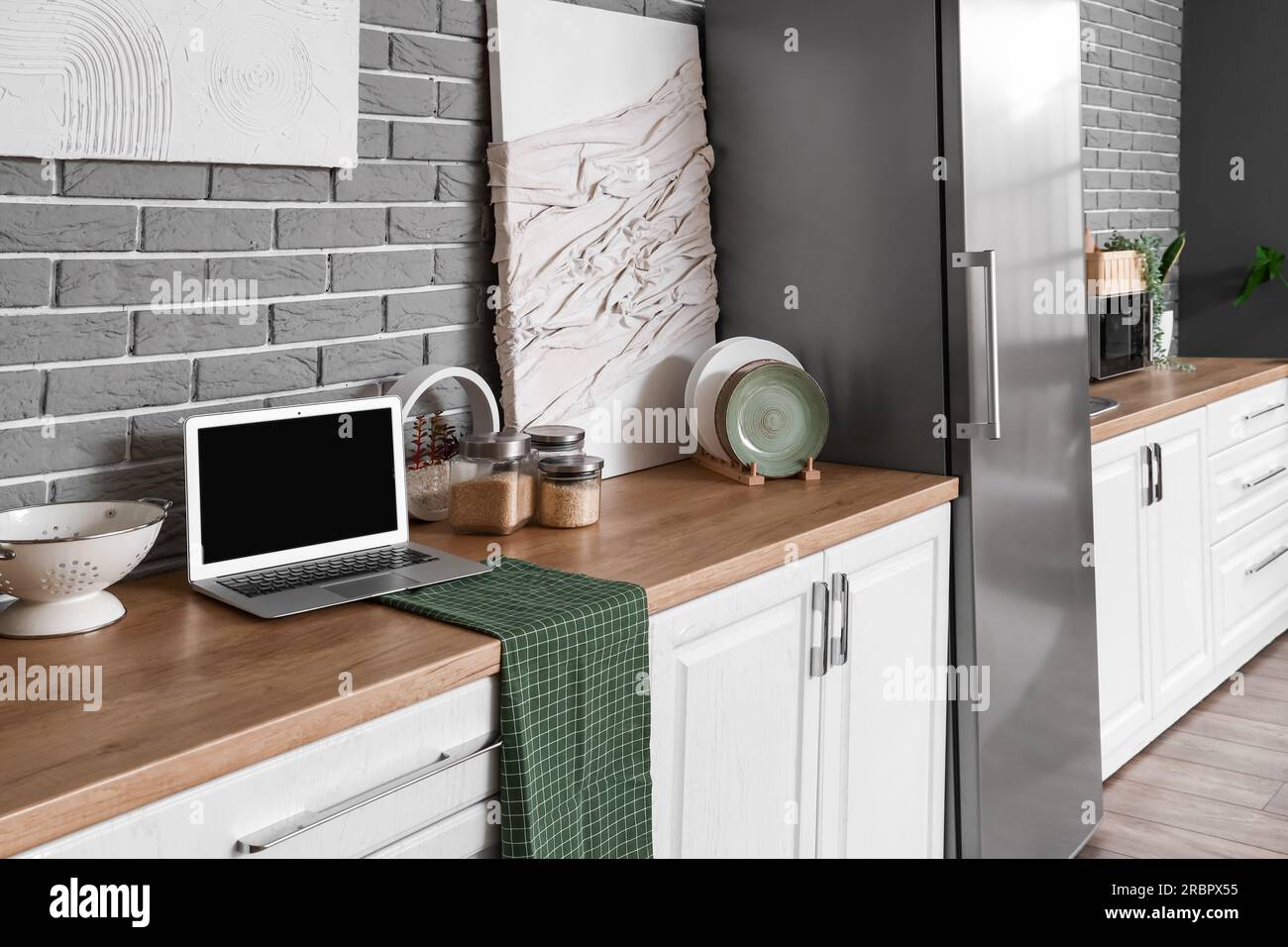 Interior of kitchen with stylish fridge, counters, laptop computer and