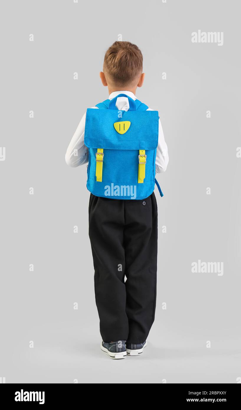 Little schoolboy with blue backpack on grey background, back view Stock ...