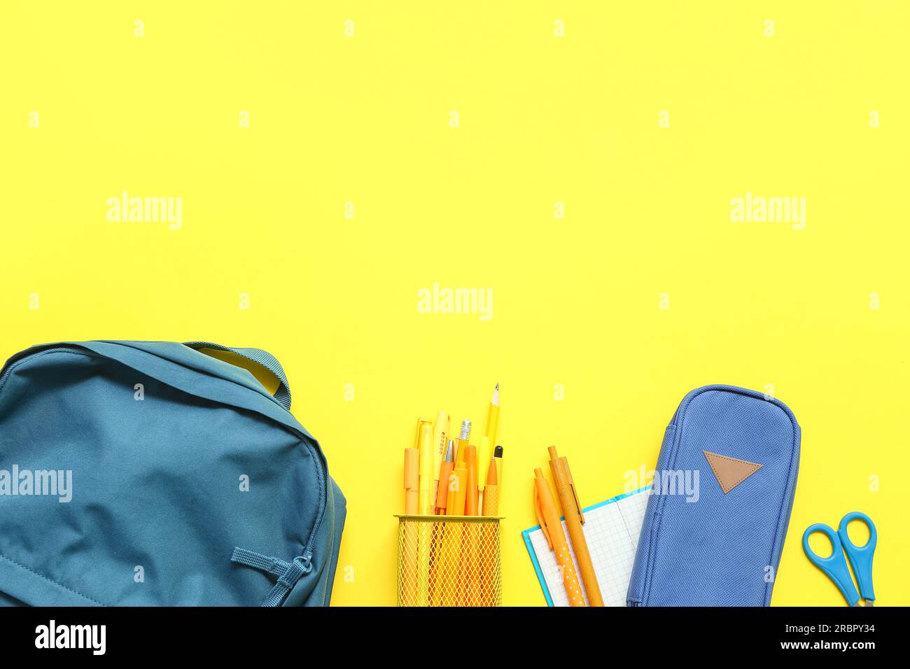 School backpack with stationery on yellow background Stock Photo