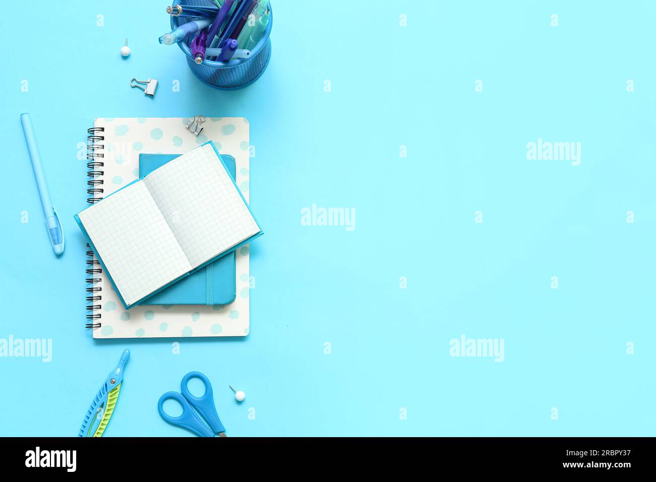 Composition with notebooks and different school stationery on blue background Stock Photo