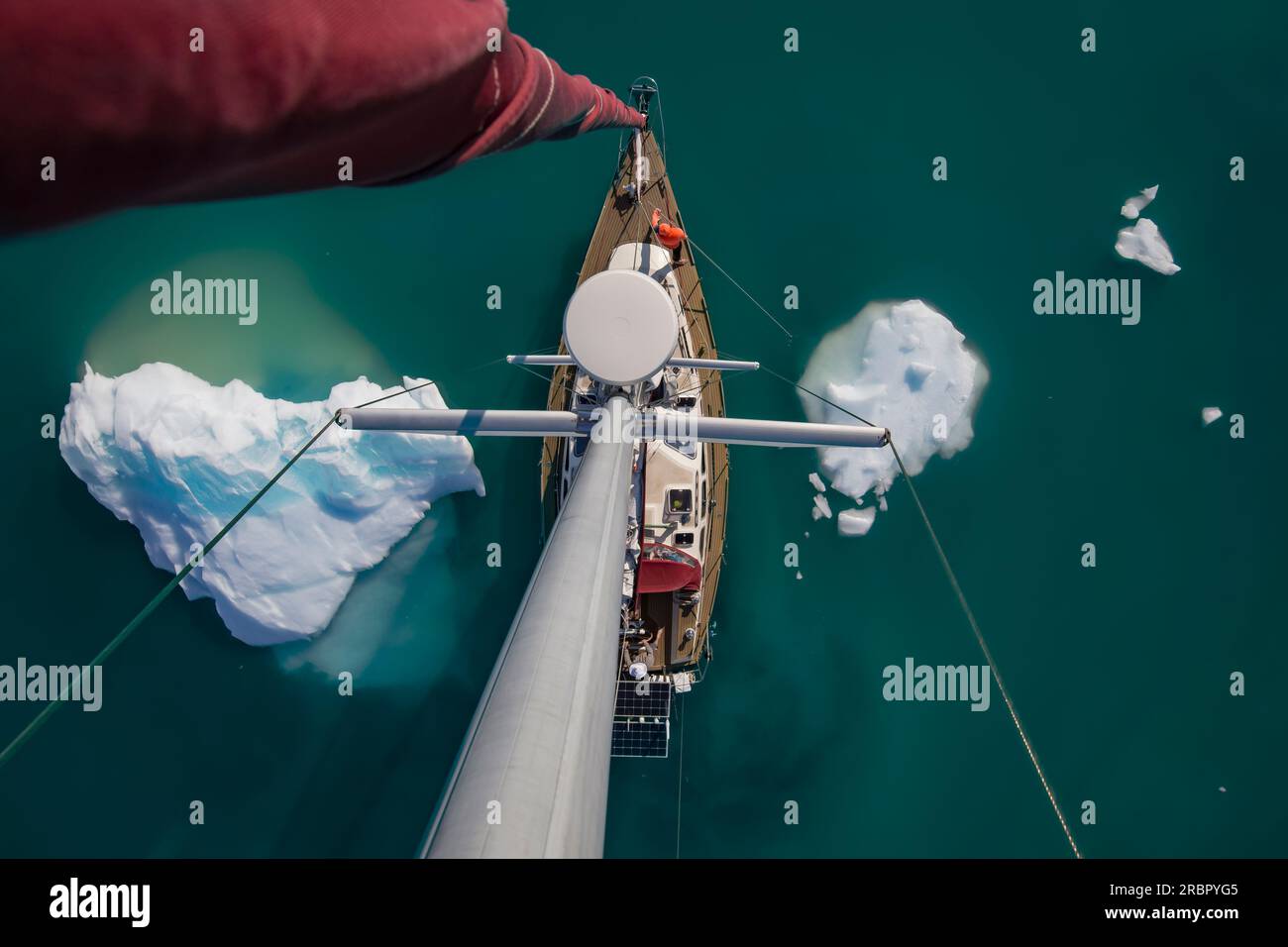 Icebergs surround Sailboat. View from the top of the mast. Beautiful turquoise water. Stock Photo