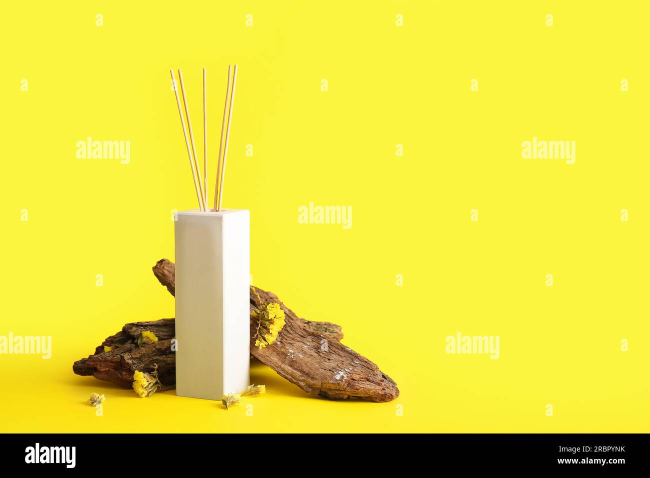 Reed diffuser and tree bark on yellow background Stock Photo - Alamy