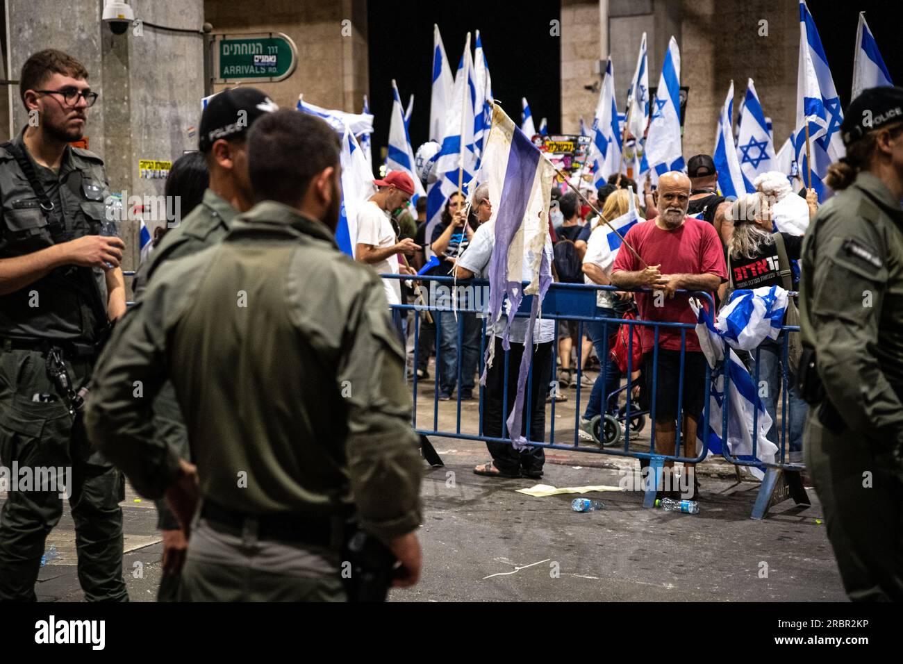 Israel. 03rd July, 2023. A protestor with a torn Israeli flag looks at border police soldiers during a demonstration against the judicial overhaul in Ben Gurion Airport. Tel Aviv, Israel. July 03th 2023. (Matan Golan/Sipa USA). Credit: Sipa USA/Alamy Live News Stock Photo