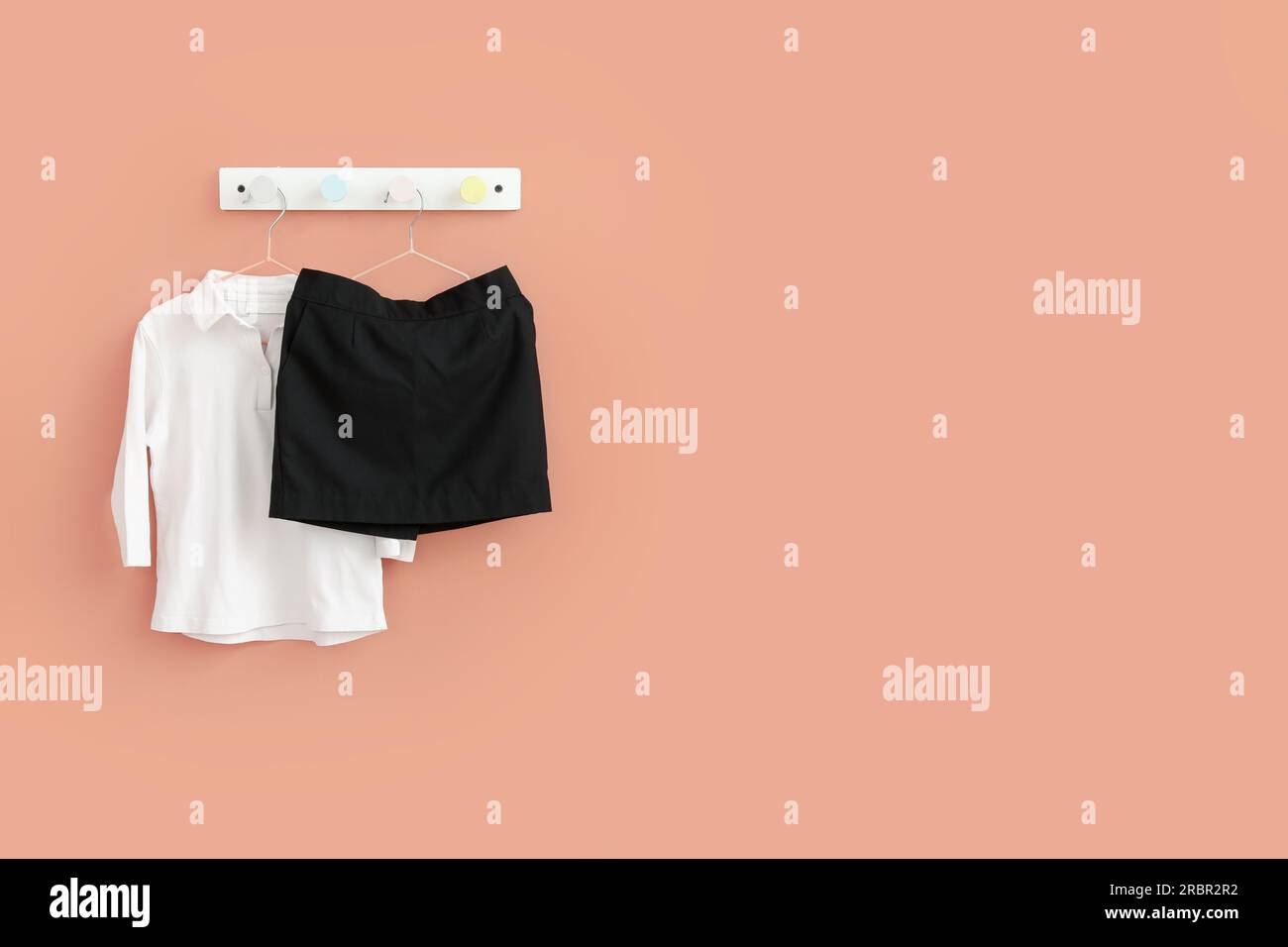Stylish school uniform hanging on beige wall in room Stock Photo - Alamy