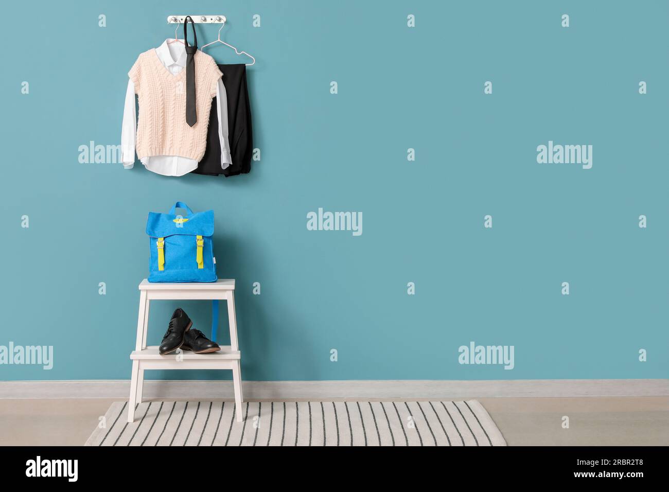Step ladder with school backpack, shoes and uniform hanging on color