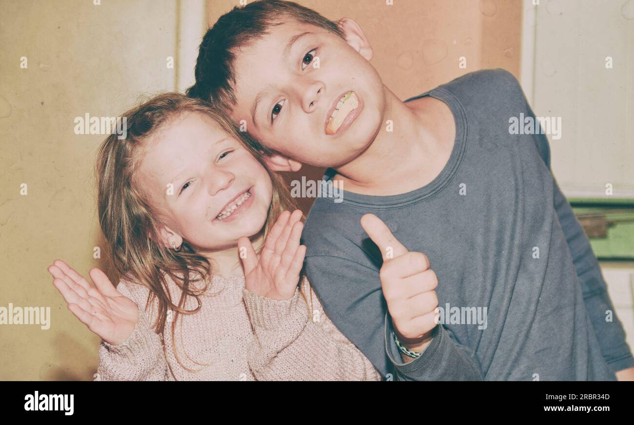Two children are making faces. Boy is giving thumb up and girl is clapping the beat. Funny and children concept. Add vintage effect. Stock Photo
