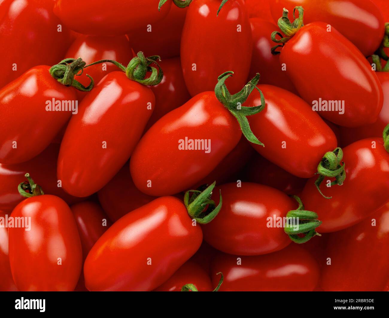 Raw Ornela cherry tomatoes macro background. Texture of small bottle shaped tomatoes. Ripe organic vegetables closeup. Healthy eating vegetarian food Stock Photo