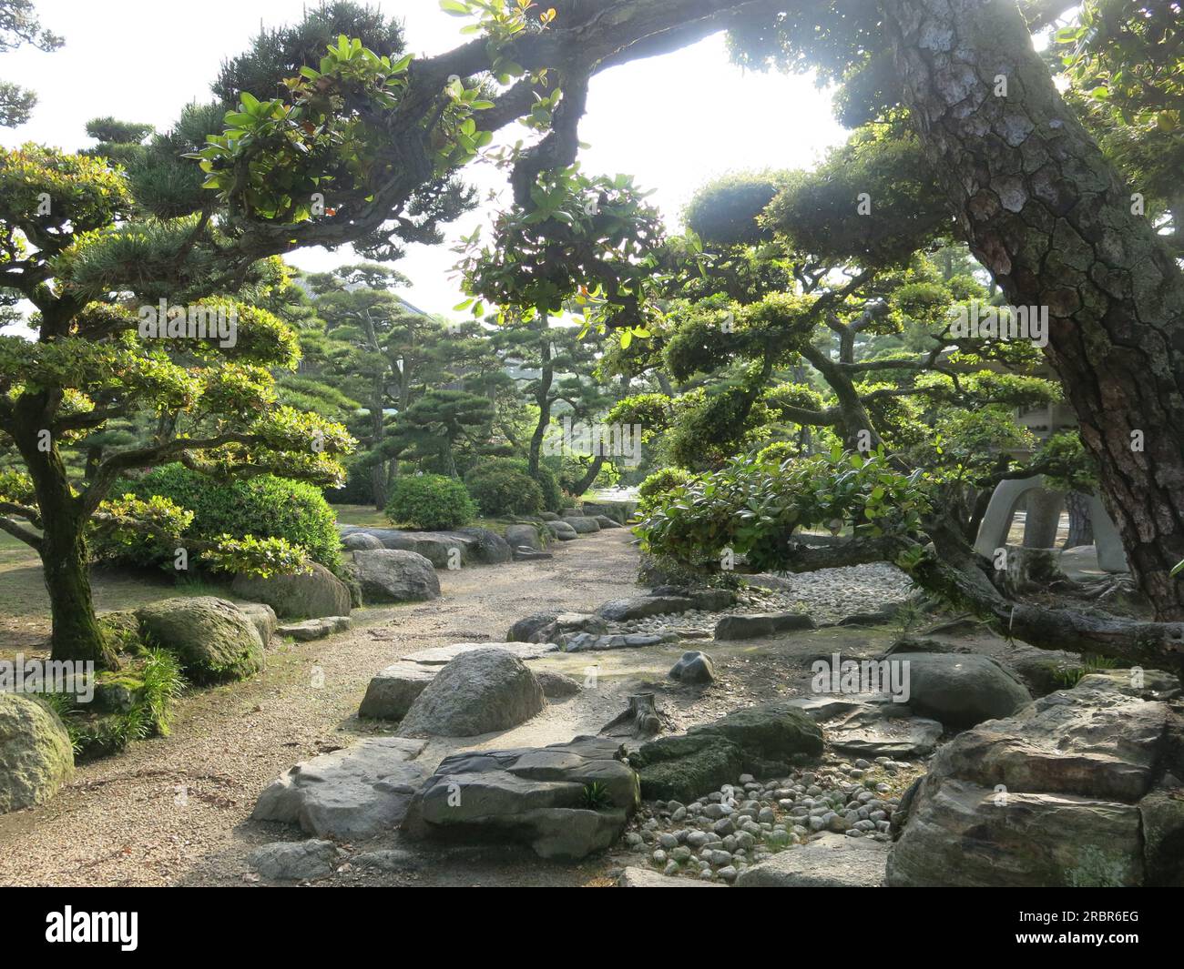 View of the beautiful grounds of Tamamo Park at the port of Takamatsu with all the Japanese elemts of pine trees, stone lanterns, pebbles & rocks. Stock Photo