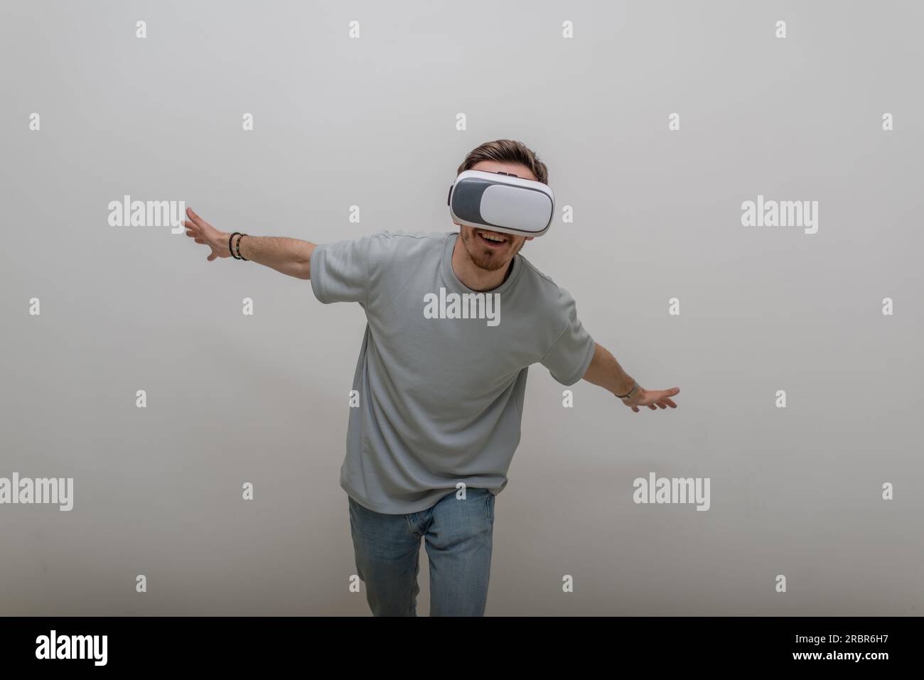 Futuristic man wearing virtual reality glasses interacts with the air in an isolated gray background. Stock Photo