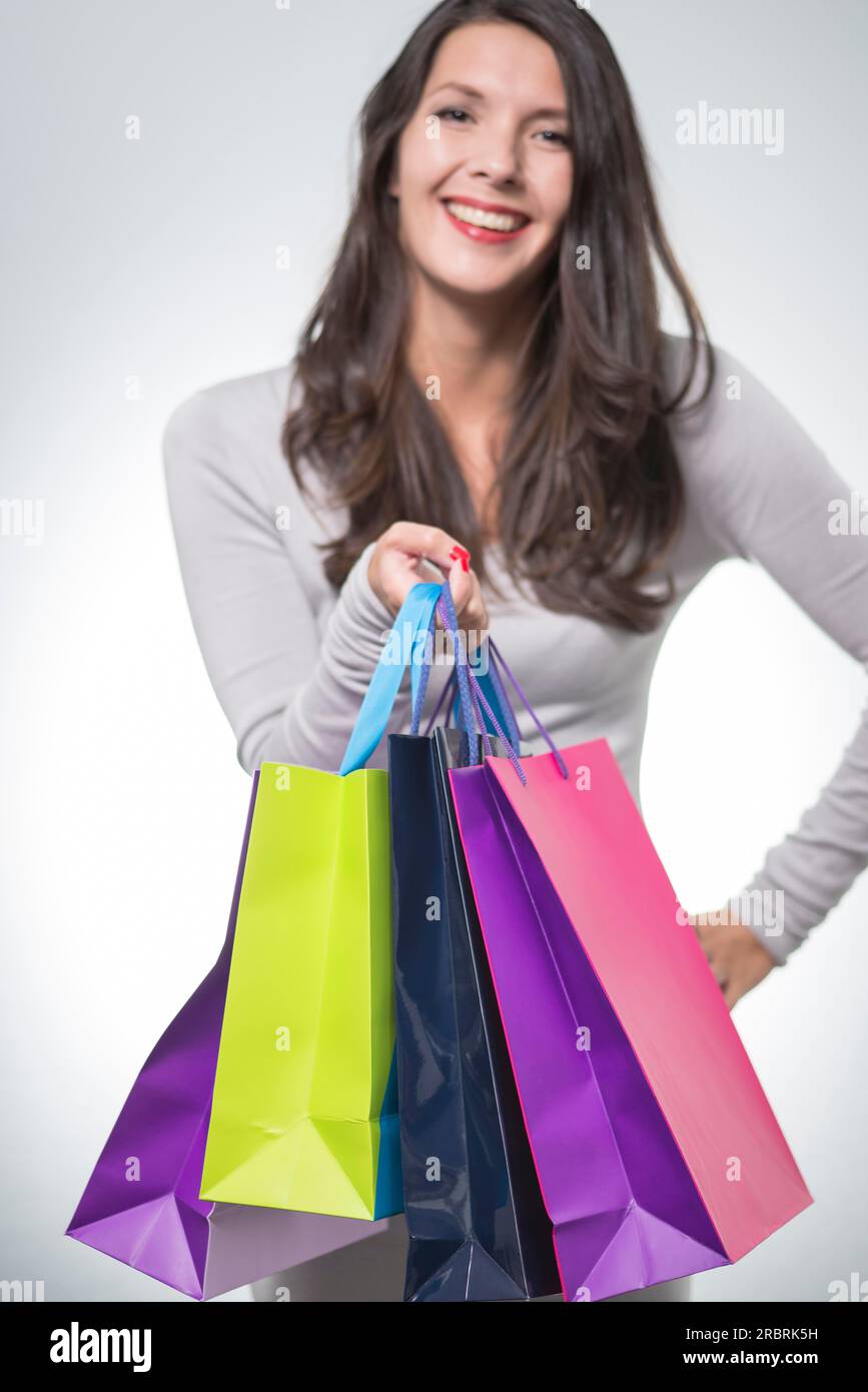 Beautiful satisfied woman holding an array of colourful shopping bags smiling happily at her successful spending spree, slective focus Stock Photo
