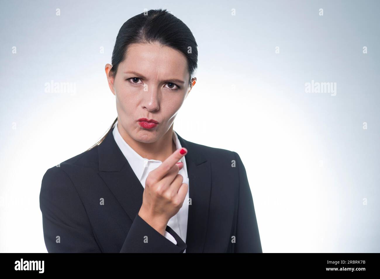 Stern young business woman or manageress making a finger gesture of displeasure as she frowns at the camera, studio portrait with copyspace Stock Photo