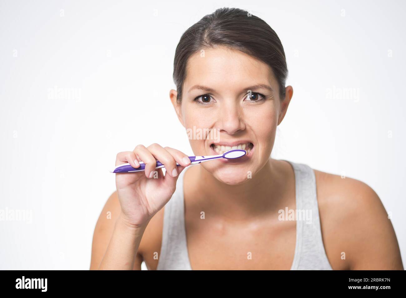 Attractive woman practising dental hygiene brushing her teeth with a