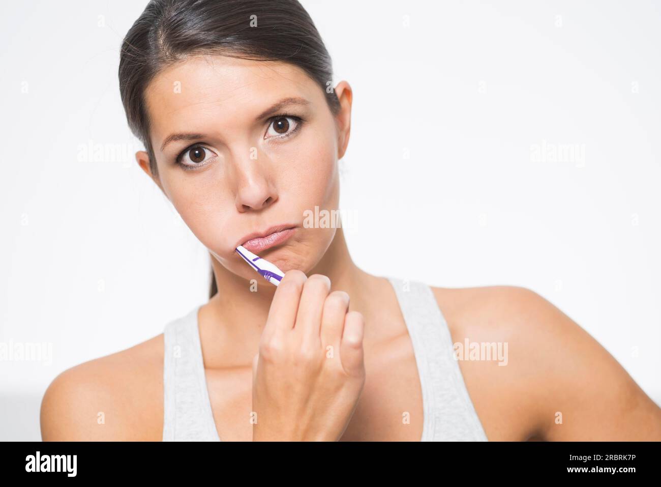 Attractive woman practising dental hygiene brushing her teeth with a