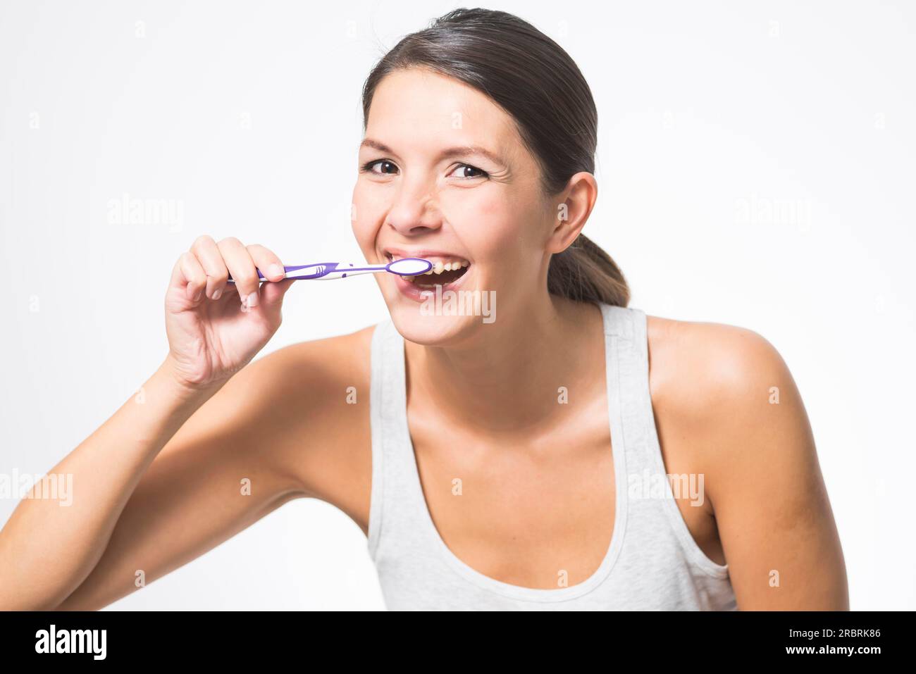 Attractive woman practising dental hygiene brushing her teeth with a