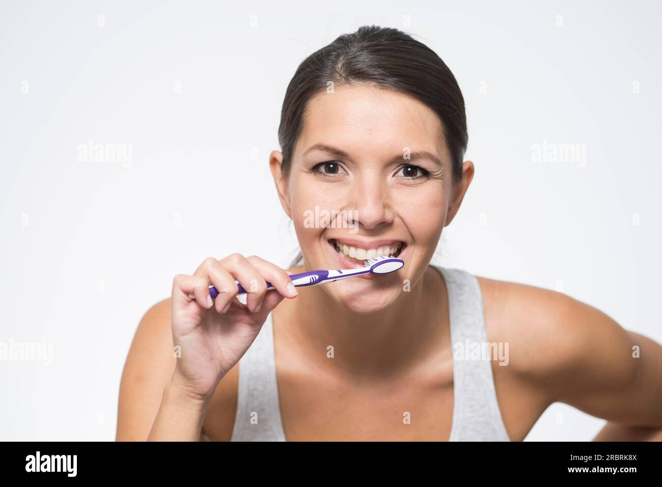 Attractive woman practising dental hygiene brushing her teeth with a