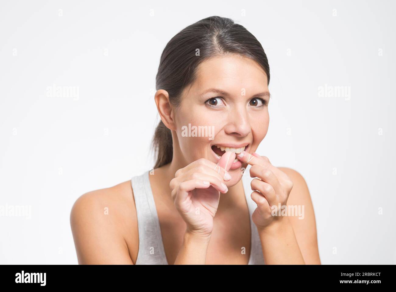 Woman flossing her teeth with dental floss to remove any food particles