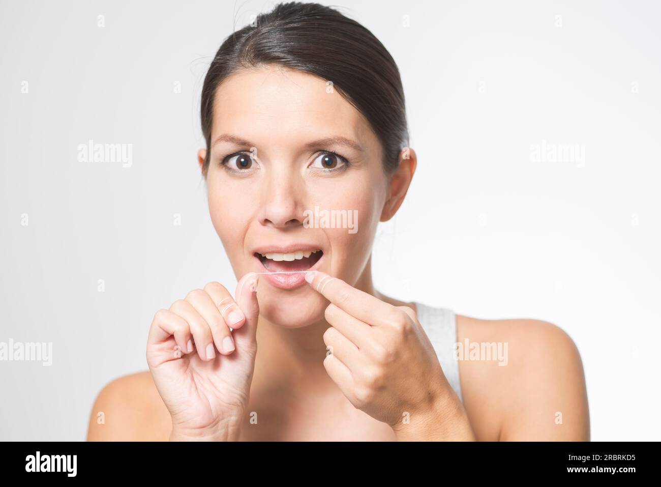Woman flossing her teeth with dental floss to remove any food particles