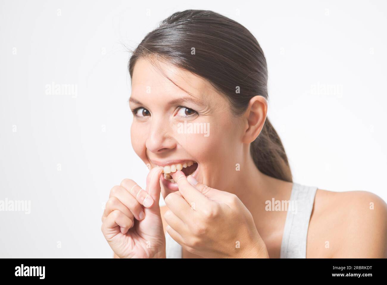 Woman flossing her teeth with dental floss to remove any food particles