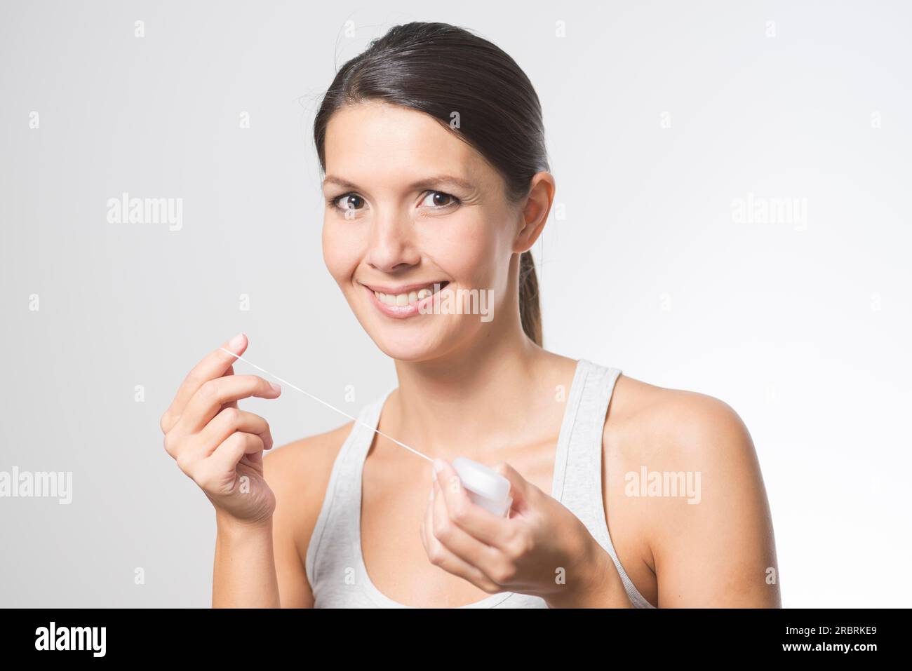 Woman flossing her teeth with dental floss to remove any food particles